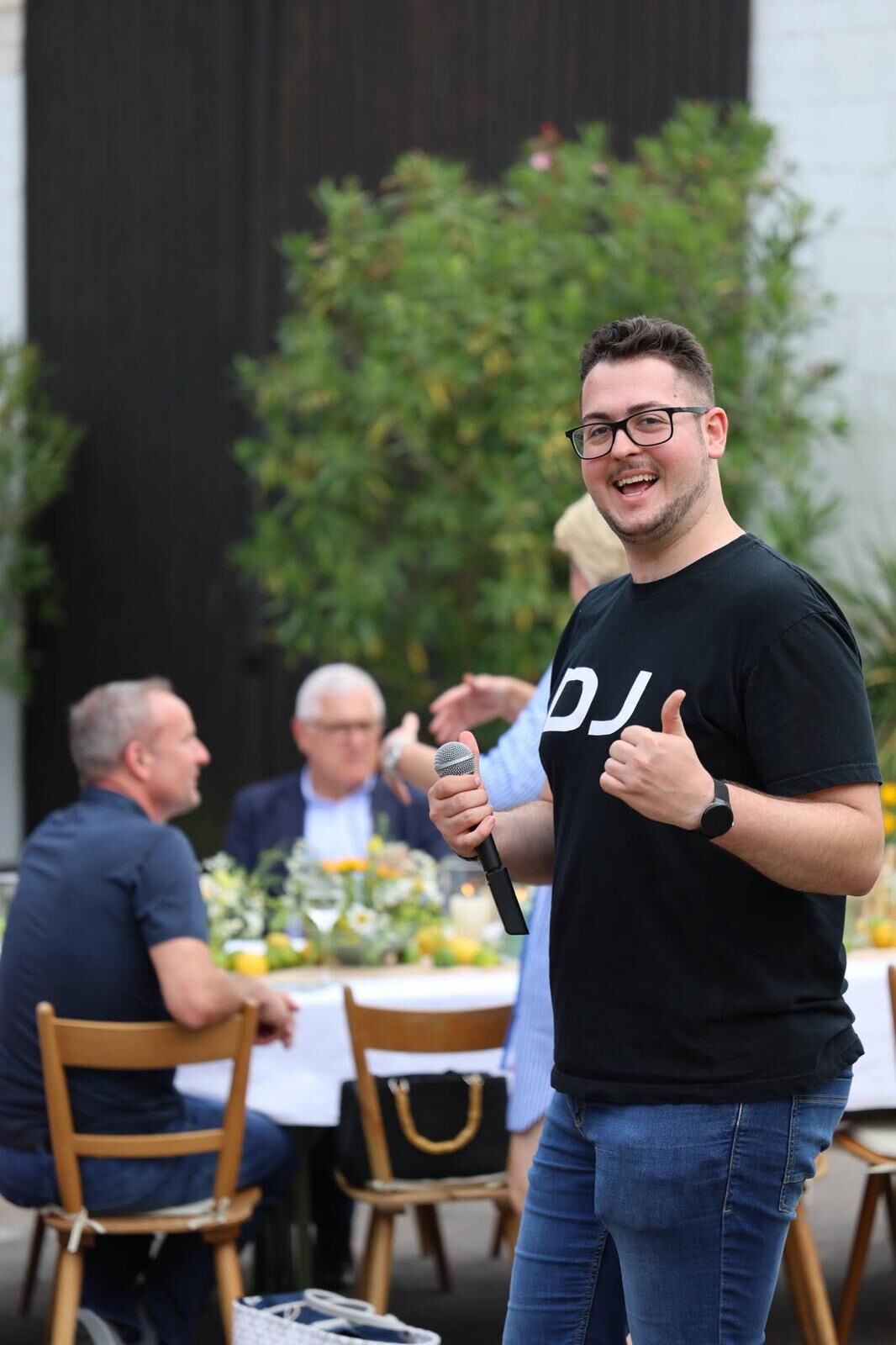 DJ Kim Schehl mit Mikrofon auf einer Gartenfeier