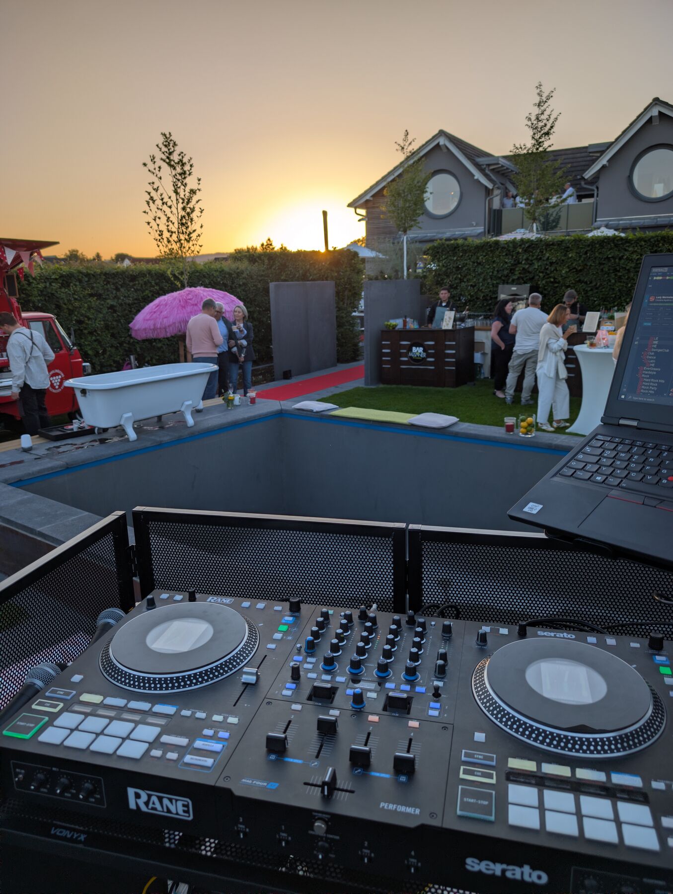 DJ-Pult mit Blick auf eine Gartenfeier bei Sonnenuntergang